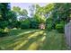 View of a well-manicured backyard with a red storage shed and mature trees at 3518 Woodale Rd, Indianapolis, IN 46234