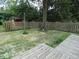 Fenced backyard with mature trees, grass, and a view of the shed, plus a deck at 3518 Woodale Rd, Indianapolis, IN 46234
