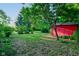 Backyard with green lawn, a red storage shed, and mature trees offering shade at 3518 Woodale Rd, Indianapolis, IN 46234