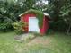 Red shed with an aluminum door and an overgrowth of green vines, providing backyard storage at 3518 Woodale Rd, Indianapolis, IN 46234