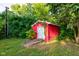 Exterior view of a red storage shed surrounded by green grass and mature trees at 3518 Woodale Rd, Indianapolis, IN 46234