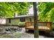 Home exterior with a small deck, patio, lush green landscaping, and mature trees for outdoor enjoyment at 4309 Clayburn Dr, Indianapolis, IN 46268