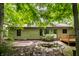 Home exterior featuring a deck, mature trees, natural landscaping, and partial brick patio for outdoor living at 4309 Clayburn Dr, Indianapolis, IN 46268