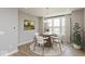 Well-lit dining area features a round table with modern chairs, complemented by natural light and hardwood flooring at 6038 Windsor Dr, McCordsville, IN 46055