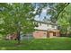 A spacious backyard is showcased, featuring a lush green lawn, brick exterior, and mature trees at 6838 Johnson Rd, Indianapolis, IN 46220