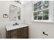 Bright bathroom with a wood vanity, white countertop, and a modern mirror and light fixture at 6838 Johnson Rd, Indianapolis, IN 46220