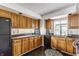 Galley kitchen featuring wooden cabinets, black appliances and updated countertops at 7685 River Rd, Indianapolis, IN 46240