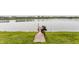 Scenic view of a tranquil lake with a wooden dock and boat, surrounded by lush green grass at 7685 River Rd, Indianapolis, IN 46240