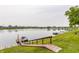 Peaceful lake view from a grassy slope, featuring a wooden dock, boat, and waterfront homes at 7685 River Rd, Indianapolis, IN 46240
