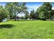 Spacious front yard with mature trees and well-manicured lawn, providing a welcoming curb appeal at 8019 E Hanna Ave, Indianapolis, IN 46239
