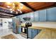 A spacious kitchen featuring blue cabinets, butcher block counters, stainless steel appliances, and a unique wood ceiling at 8019 E Hanna Ave, Indianapolis, IN 46239
