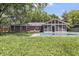 Expansive backyard showcasing a covered pool, brick house, and lush greenery at 8246 Windcombe Blvd, Indianapolis, IN 46240