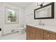 Bathroom featuring tiled shower, window, and a beautiful vanity with a modern mirror at 8246 Windcombe Blvd, Indianapolis, IN 46240