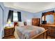 This bedroom has a large bed, wooden furniture, one window, and blue walls at 9042 Panorama Ct, Indianapolis, IN 46234
