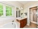 Inviting bathroom featuring a tub, separate glass shower, wood cabinets, and a large bright window at 10005 Southwind Dr, Indianapolis, IN 46256