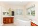 Bright bathroom with a large soaking tub, wooden cabinets, and natural light from the large window at 10005 Southwind Dr, Indianapolis, IN 46256