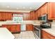 Well-lit kitchen with stainless steel appliances, wooden cabinets, tile flooring, and a garden window at 10005 Southwind Dr, Indianapolis, IN 46256
