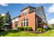 Rear exterior showcasing a brick facade, large windows, and a well-manicured lawn at 10480 Stonegate Dr, Fishers, IN 46040