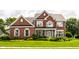 Beautiful two-story brick home with a lush green lawn and colorful flower beds at 10480 Stonegate Dr, Fishers, IN 46040