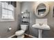 Neat powder room with pedestal sink, decorative mirror, and storage shelving at 10480 Stonegate Dr, Fishers, IN 46040
