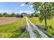 Long gravel driveway leading to a light yellow home surrounded by green and harvested farmland at 10705 N State Road 267, Brownsburg, IN 46112