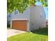 Side view of a two-story home featuring a two-car garage with a wooden door and well-kept lawn at 10775 Cyrus Dr, Indianapolis, IN 46231