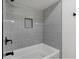 Close-up of a modern bathtub with sleek gray tiling and a recessed shelf, perfect for a relaxing soak at 10778 Haverstick Rd, Carmel, IN 46033