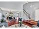 Bright living room with dark wood floors leading to an adjacent eat-in kitchen and a staircase at 1099 Saratoga Cir, Carmel, IN 46280