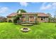 A vast backyard featuring a well-manicured lawn, a cozy fire pit, and a quaint wooden deck attached to a brick house at 1106 Summer Way Ct, Shelbyville, IN 46176