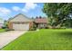 Charming brick home featuring a well-manicured lawn and attached two-car garage on a beautiful sunny day at 1106 Summer Way Ct, Shelbyville, IN 46176