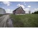 A weathered barn stands near a muddy road and grain bins, offering a glimpse of its rural charm at 17550 N 200 W, Summitville, IN 46070