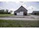 Weathered barn with sliding doors, a concrete base, and a gravel driveway, perfect for storage or restoration at 17550 N 200 W, Summitville, IN 46070