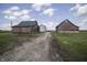 Group of barns and a grain silo set against a backdrop of green fields. Providing storage and agricultural potential at 17550 N 200 W, Summitville, IN 46070