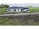 Exterior view of a white house with a dark roof, set in a rural landscape with a dirt driveway at 17550 N 200 W, Summitville, IN 46070