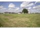 Sprawling farmland featuring multiple outbuildings and silos beneath a blue sky dotted with fluffy white clouds at 17550 N 200 W, Summitville, IN 46070