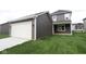 View of two-story home with dark siding, white garage door and a green front lawn at 1821 Real St, Indianapolis, IN 46240