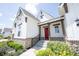 View of covered entry way with stone facade and red door, enhanced by colorful landscaping at 1872 Wellpark Dr, Westfield, IN 46074
