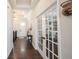 Hallway showcasing dark wood floors, leading to a home office with glass French doors and a transom window at 1872 Wellpark Dr, Westfield, IN 46074