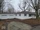 A charming single-story white home with attached garage, blue shutters and a spacious front yard at 200 S East St, Indianapolis, IN 46204