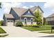 Rear exterior view showcasing the home's blue siding, stone accents, attached garage and expansive driveway at 3720 Abney Highland Dr, Zionsville, IN 46077