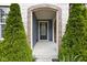 Inviting front porch with brick archway, evergreen shrubbery and black front door at 3720 Abney Highland Dr, Zionsville, IN 46077