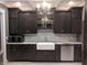 Modern kitchen with dark cabinetry, granite counters, farmhouse sink, and stainless steel appliances at 414 E Main St, Plainfield, IN 46168