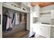 Laundry room with built-in bench, coat hooks, overhead cabinets, and a modern washer/dryer at 4279 Redwood Ct, Zionsville, IN 46077