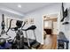 Basement gym area featuring a treadmill, elliptical machine, and access to a bedroom with wooden floors at 564 Gainesway N Dr, Greenwood, IN 46142
