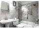 Bright bathroom featuring gray tiled walls, glass shower doors, and a modern vanity with a pedestal sink at 5736 Primrose Ave, Indianapolis, IN 46220