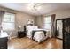 Comfortable bedroom features a queen bed, hardwood floors, neutral walls, and natural light from two windows at 5736 Primrose Ave, Indianapolis, IN 46220
