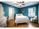 Stylish bedroom with blue walls, ceiling fan, light-colored wood floors, and a bed with white bedding and pillows at 5736 Primrose Ave, Indianapolis, IN 46220