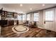 Cozy living room featuring a wet bar, hardwood floors, neutral walls, and natural light from large windows at 5736 Primrose Ave, Indianapolis, IN 46220