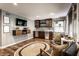 Well-lit living room showcases a wet bar, mounted TV, hardwood floors, light gray walls and two cozy armchairs at 5736 Primrose Ave, Indianapolis, IN 46220