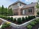 Brick home featuring stone patio, garden boxes, stone wall, manicured lawn, and professional landscaping at 5775 Coopers Hawk Dr, Carmel, IN 46033